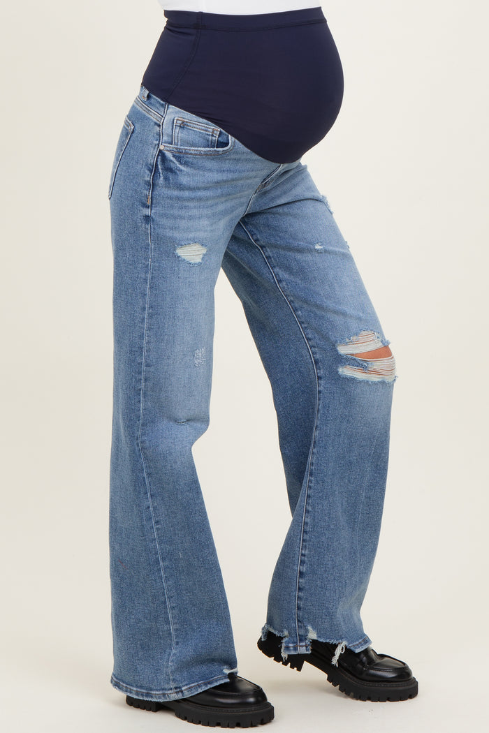 woman wearing distressed blue maternity jeans with a navy belly panel and a visible baby bump