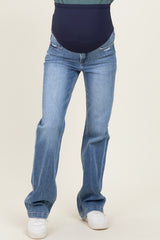 woman wearing blue maternity jeans with a dark blue belly panel and a relaxed fit, paired with white sneakers