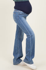 woman wearing blue flared maternity jeans with a fitted belly panel and showing off her baby bump