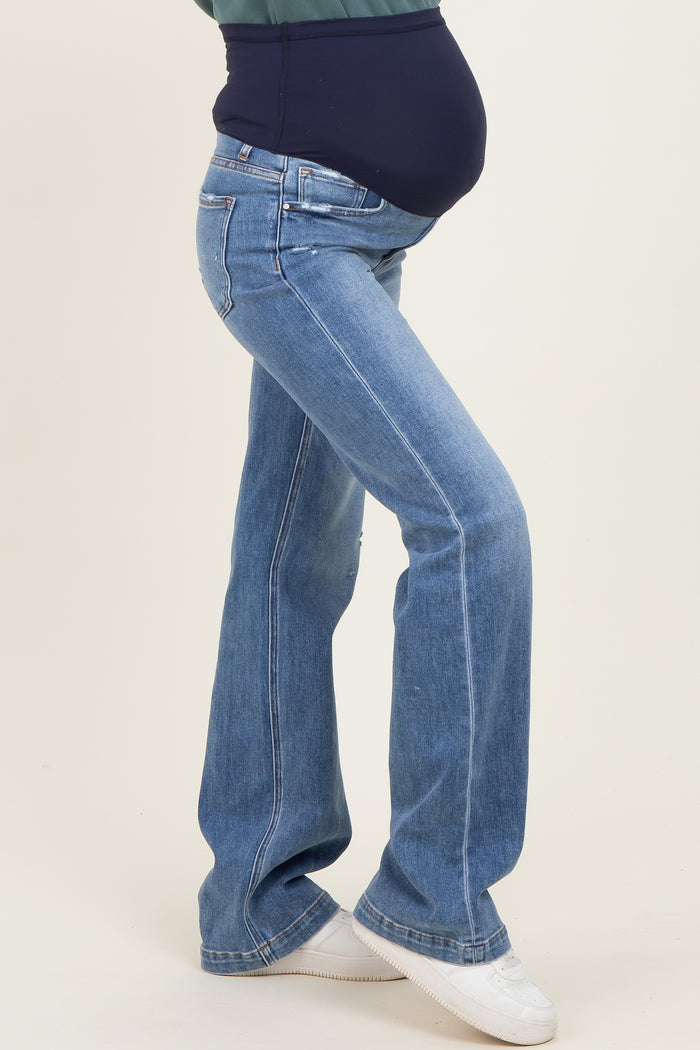 woman wearing blue flared maternity jeans with a fitted belly panel and showing off her baby bump