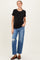 woman wearing a black short sleeve maternity top and distressed denim jeans, with a visible baby bump