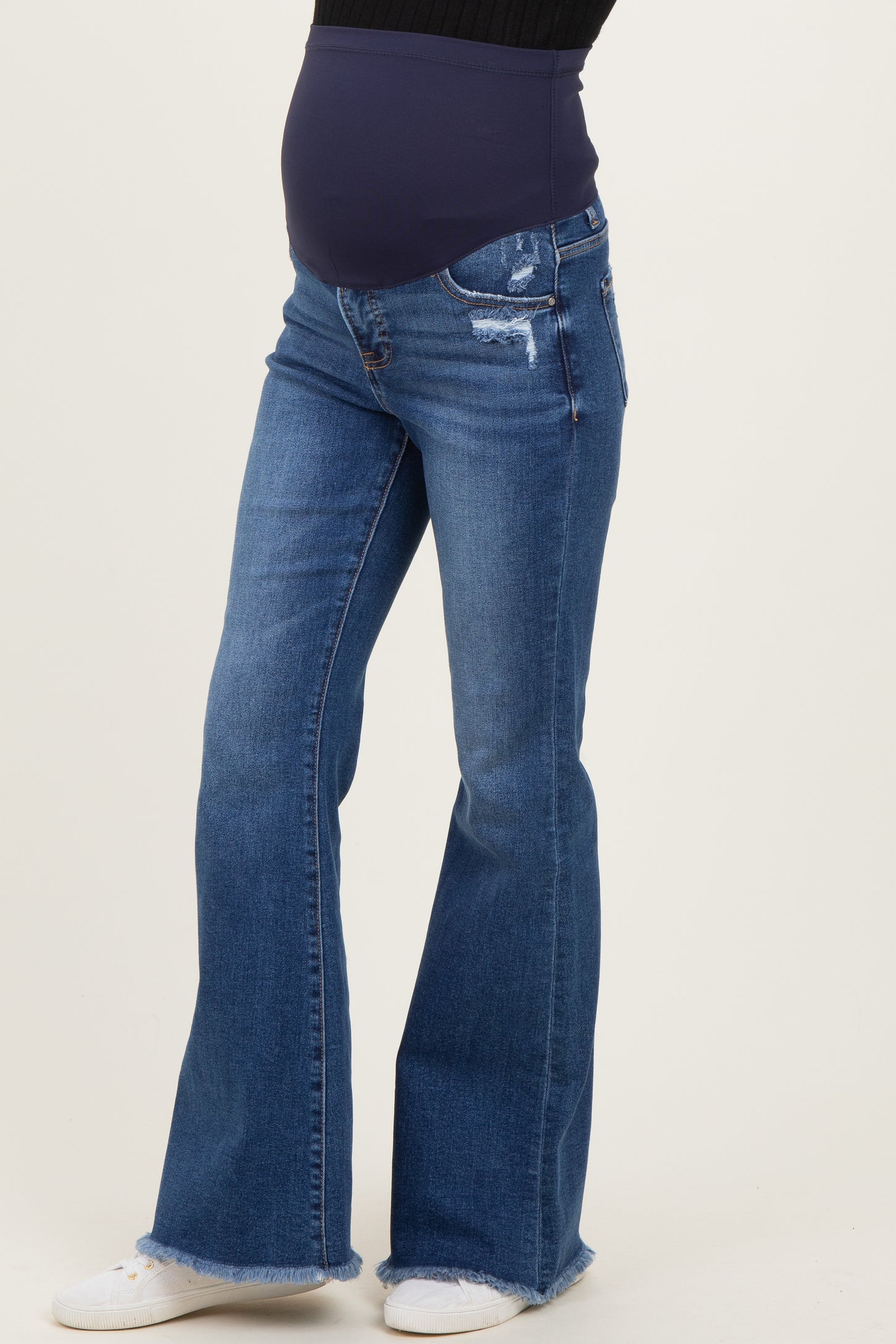 woman wearing dark blue maternity flared jeans with a distressed finish and a supportive over-the-bump waistband