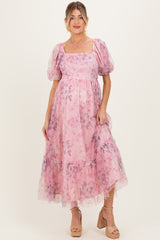 woman wearing a pink floral maternity dress with puff sleeves and a tiered skirt