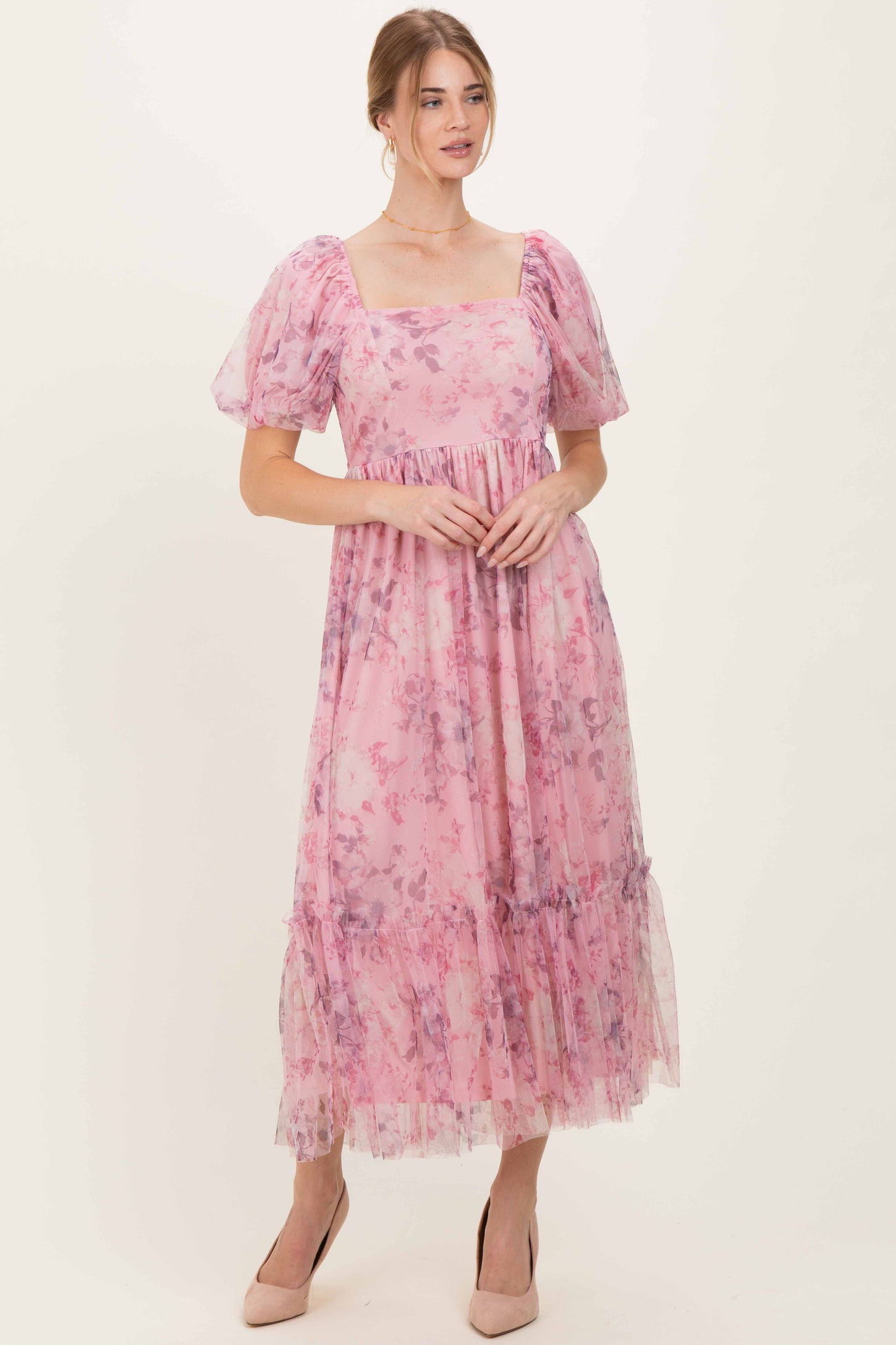 woman wearing a pink floral maxi dress with puff sleeves and a tiered hemline