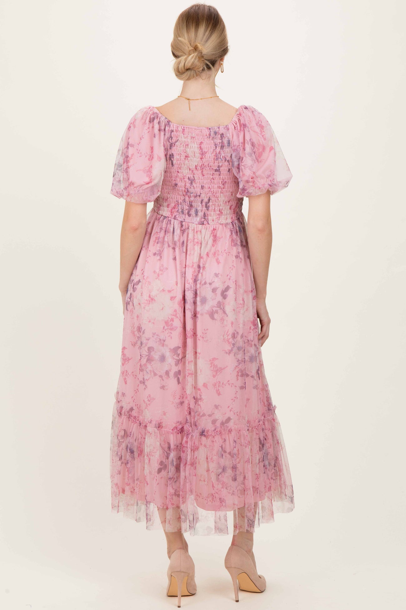 woman wearing a pastel pink floral maxi dress with puff sleeves and a smocked bodice, shown from the back