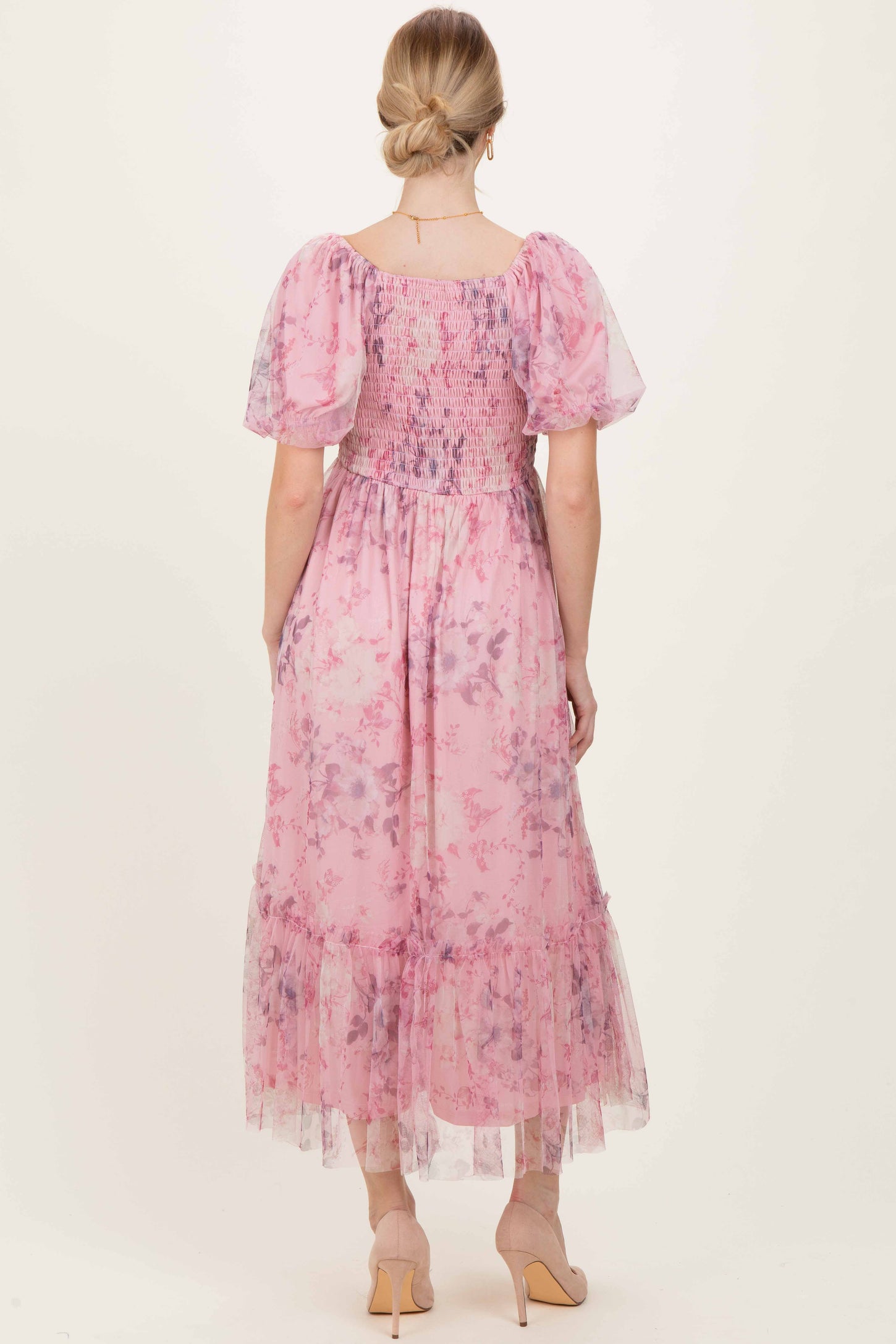 woman wearing a pastel pink floral maxi dress with puff sleeves and a smocked bodice, shown from the back