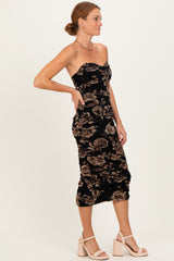 woman wearing a black floral midi dress with a strapless design and ruched detailing