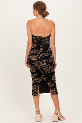 woman wearing a black floral velvet midi dress with a fitted silhouette and back slit