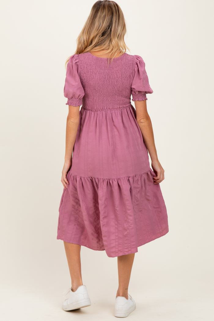 woman wearing a pink maternity dress with puff sleeves and tiered skirt, showing her back