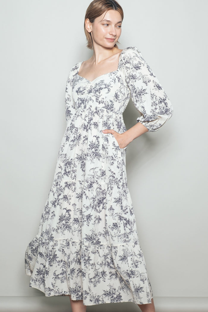 woman wearing a white floral print maxi dress with puff sleeves and side pockets