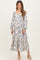 woman wearing a long sleeve floral maternity dress with a flowing skirt and visible baby bump