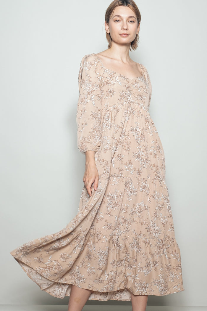 woman wearing a beige floral tiered maxi dress with long sleeves and a square neckline