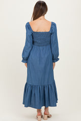 woman wearing a denim smocked maternity dress with long sleeves and a ruffled hem