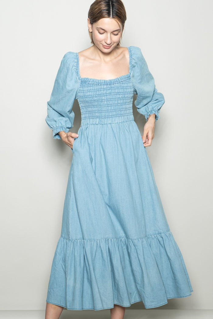 woman wearing a light blue denim maxi dress with a smocked bodice and puff sleeves