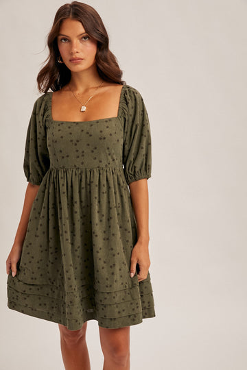 woman wearing a green puff sleeve square neck dress with floral pattern and a relaxed fit