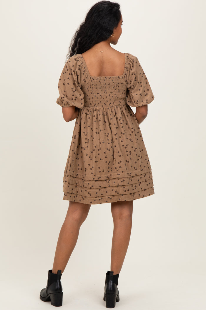 woman wearing a brown maternity dress with puff sleeves and floral patterns, back view
