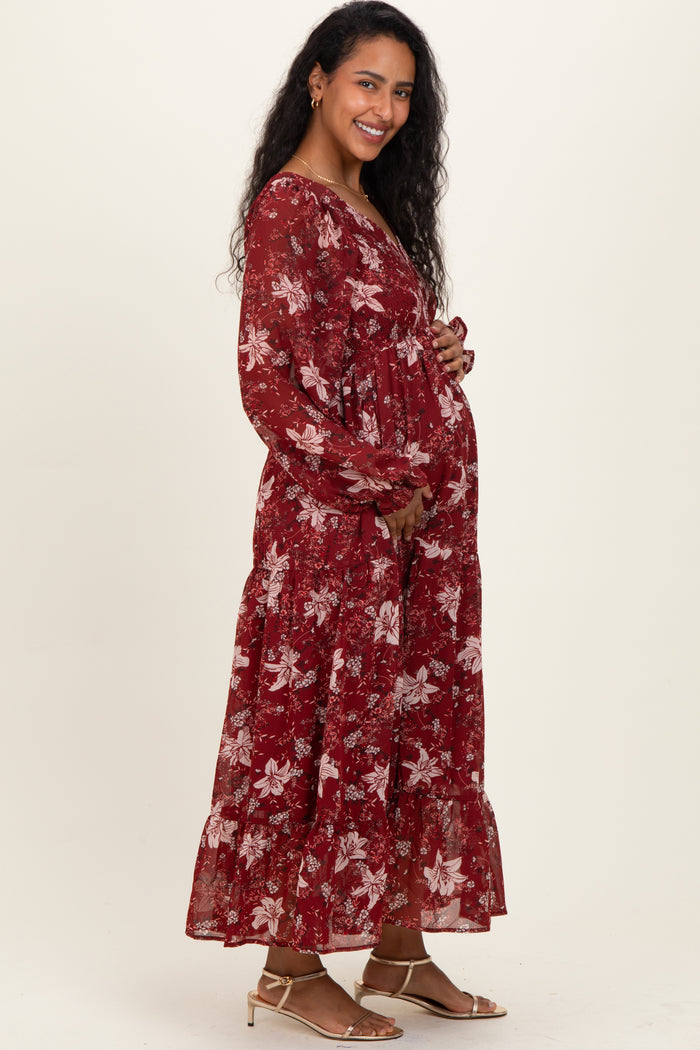 woman wearing a burgundy floral long sleeve maternity dress and holding her baby bump