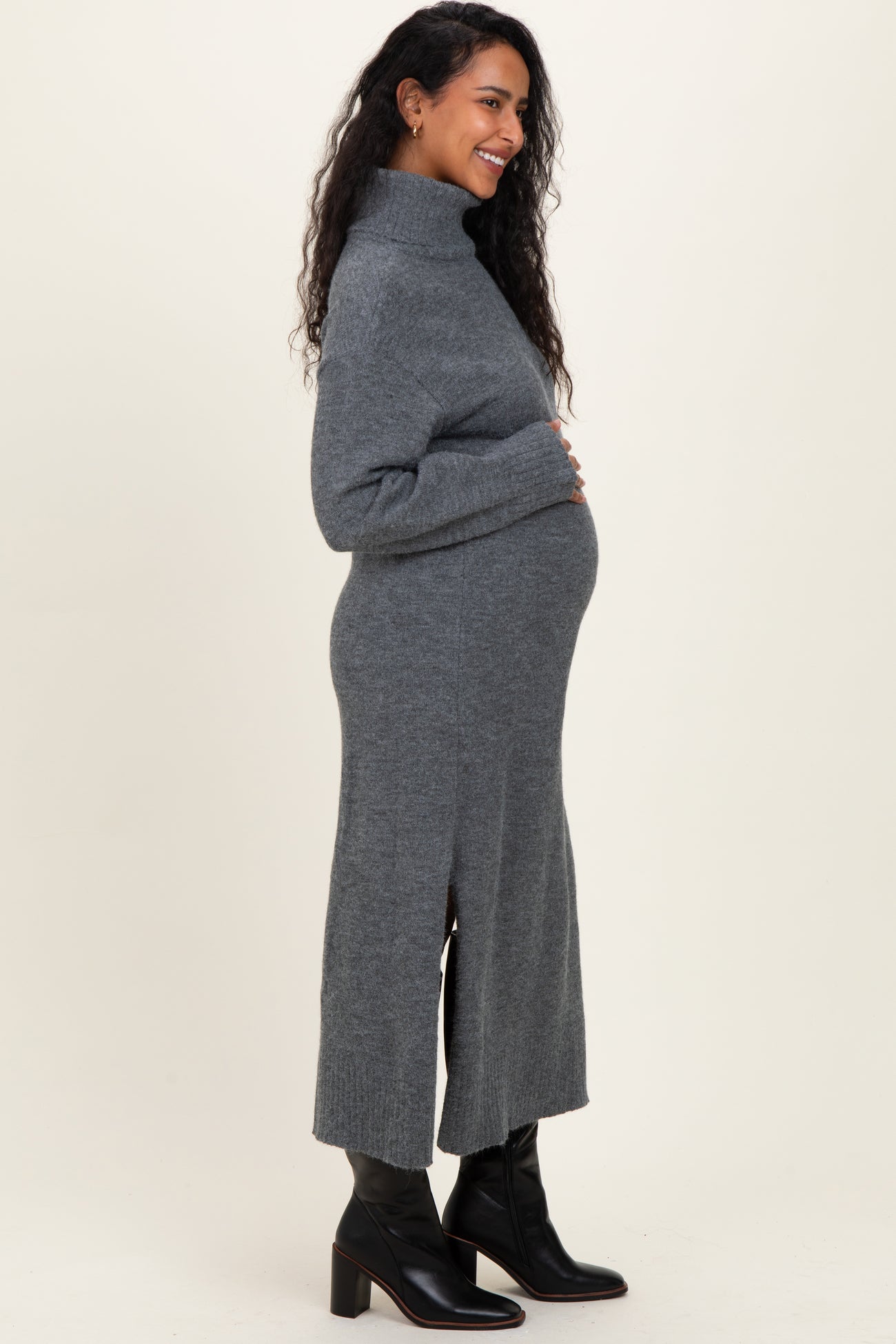 woman wearing a grey turtleneck maternity dress with side slits and a visible baby bump