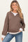 woman wearing a brown maternity sweatshirt with white ribbed accents and a relaxed fit, smiling at the camera