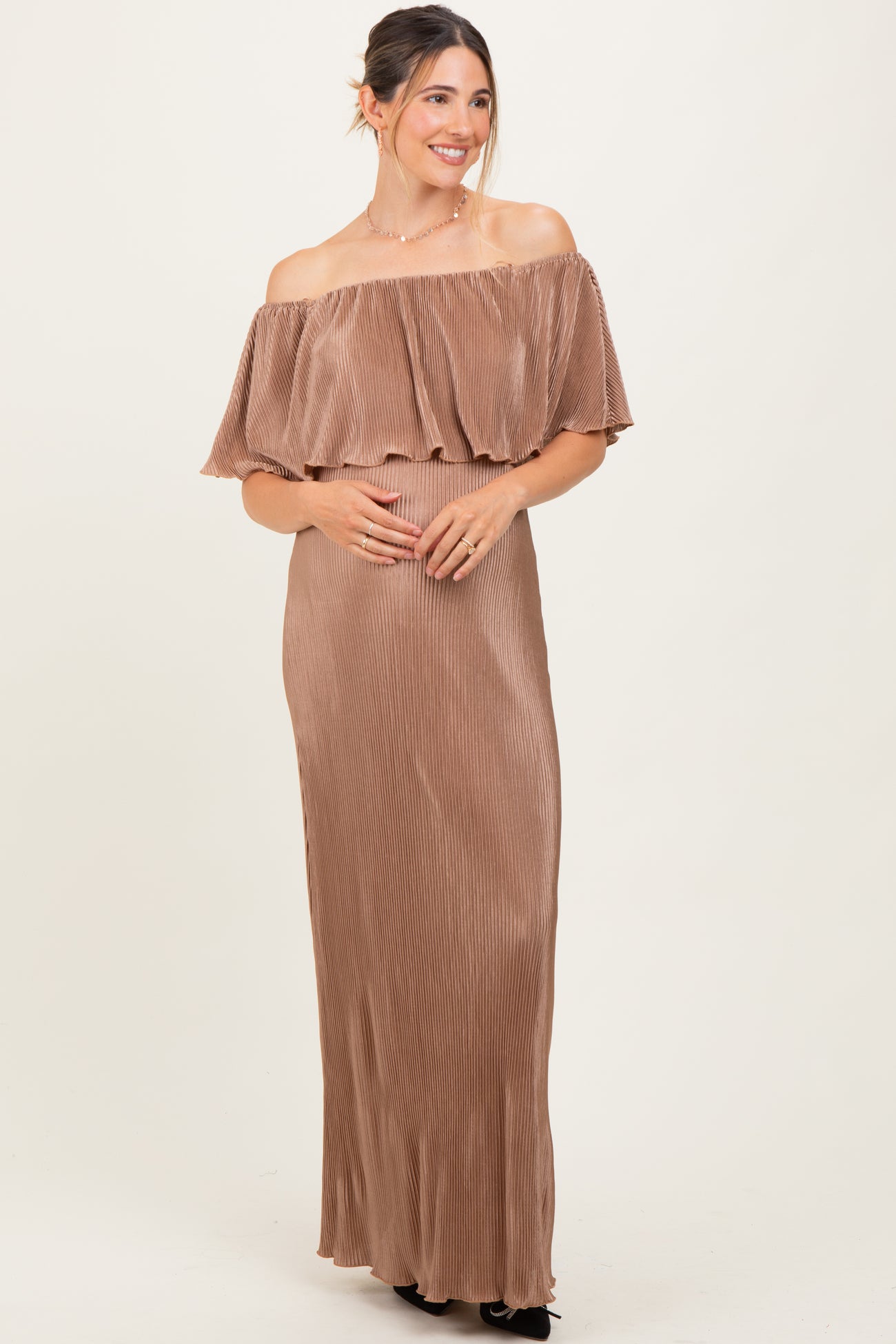 woman wearing a brown off-the-shoulder maternity dress with ruffle details and holding her baby bump