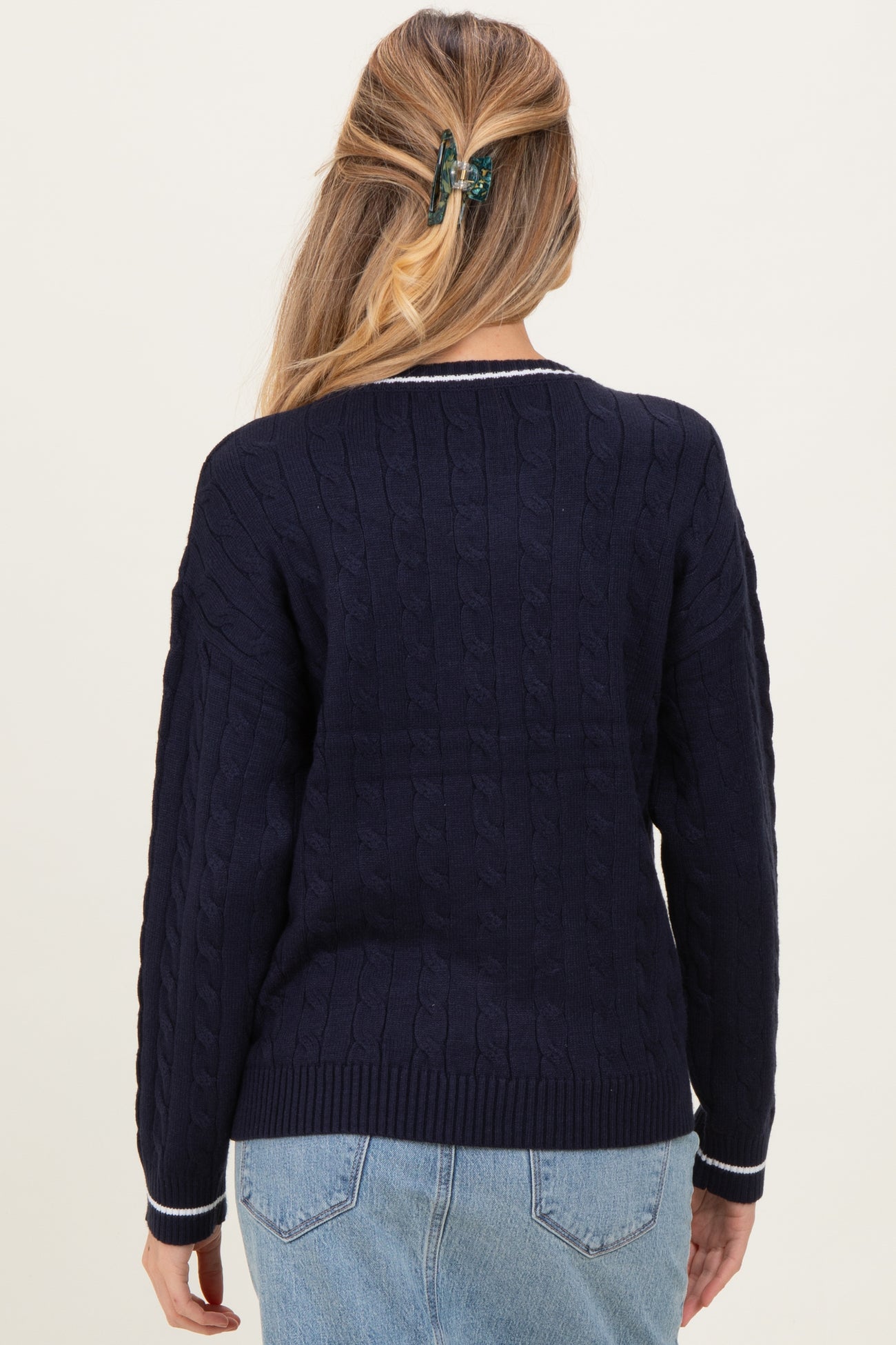 woman wearing a navy blue cable knit maternity sweater with contrast trim, viewed from the back