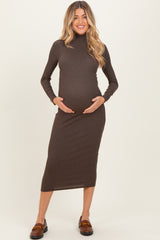woman wearing a brown long sleeve maternity dress and holding her baby bump