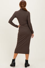 woman wearing a brown long sleeve knitted midi dress, viewed from the back, paired with black ankle boots