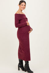 woman wearing a burgundy off-the-shoulder maternity dress and cradling her baby bump