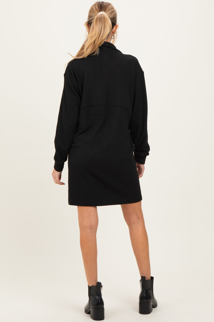 woman wearing a black maternity dress with long sleeves and a back yoke detail, showing her back while standing
