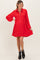 woman wearing a red maternity dress with a button-down front and bell sleeves, holding a baby bump