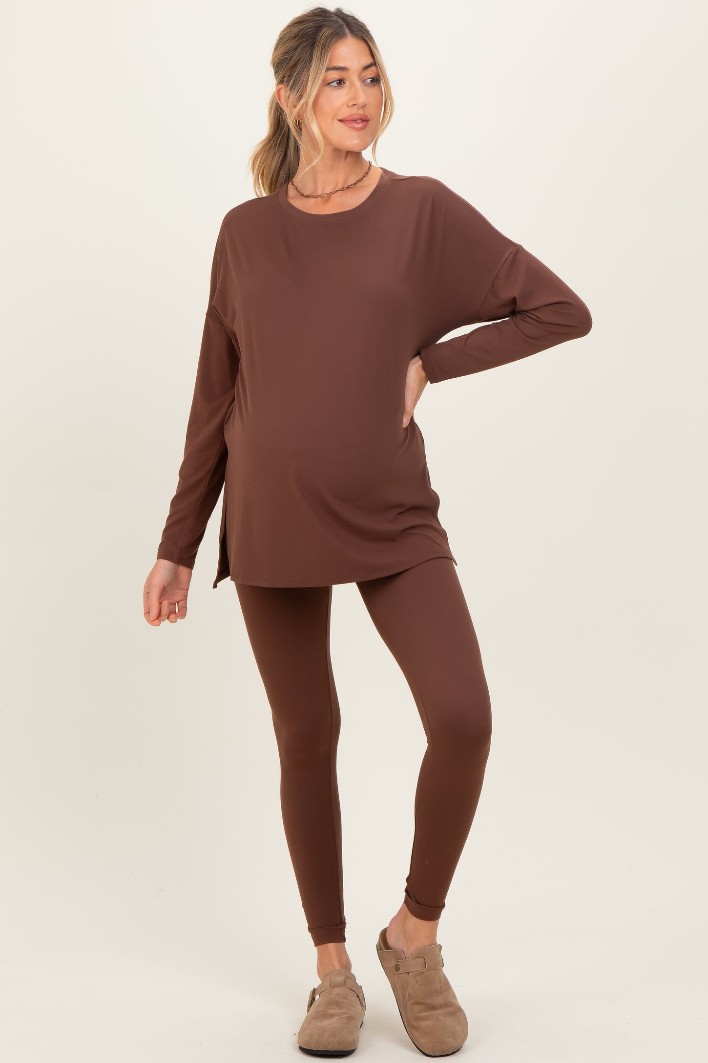 woman wearing a brown long sleeve maternity top and matching leggings, showing her baby bump