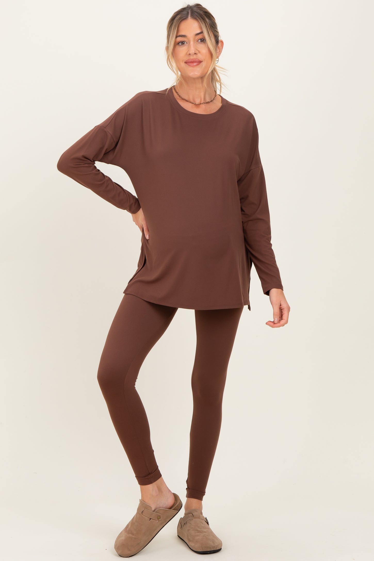 woman wearing a brown maternity wear long sleeve top and matching leggings, with a visible baby bump
