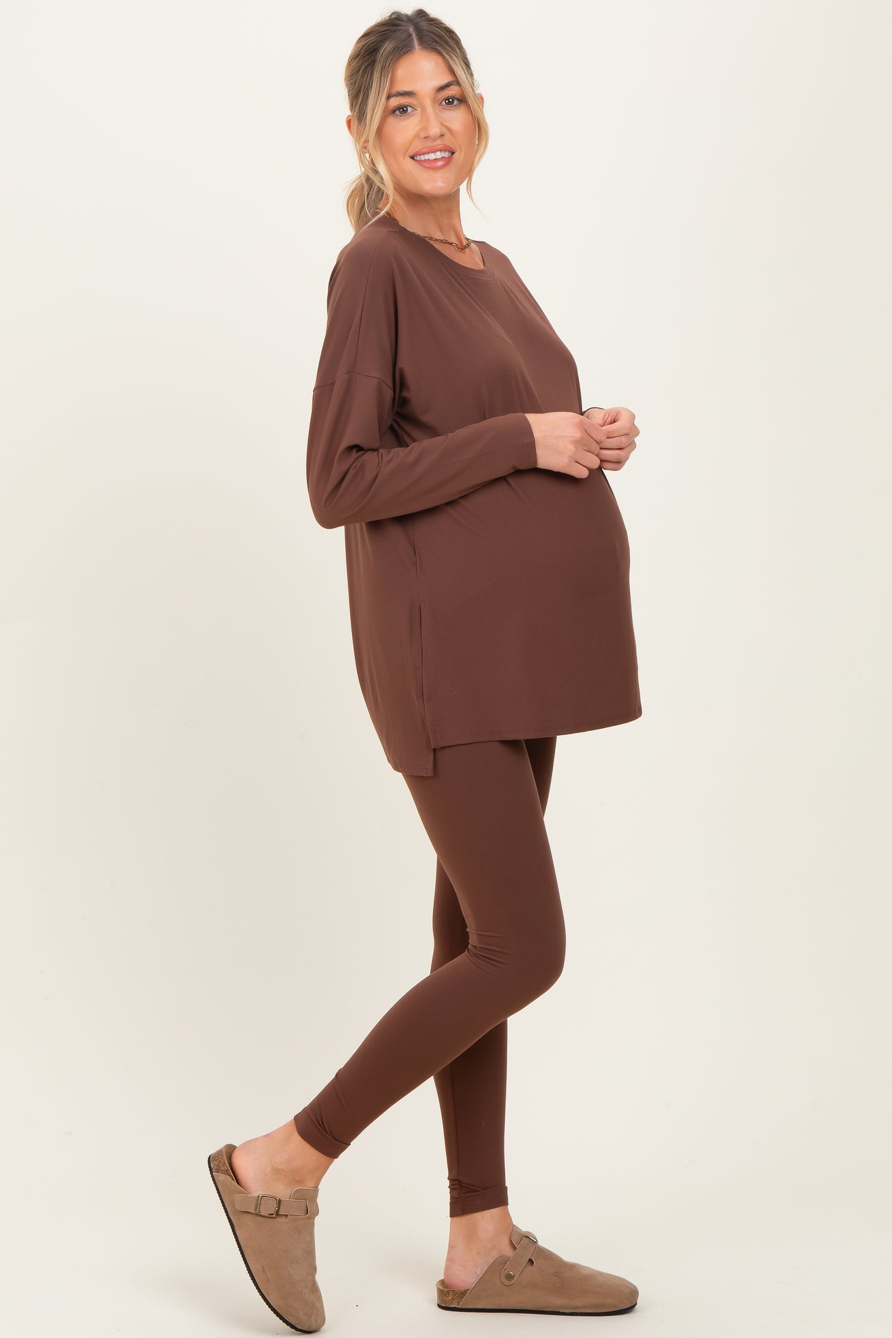 woman wearing a brown maternity long sleeve top and brown leggings, showcasing a baby bump