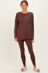 woman wearing a brown oversized long sleeve top with matching leggings and fluffy slippers
