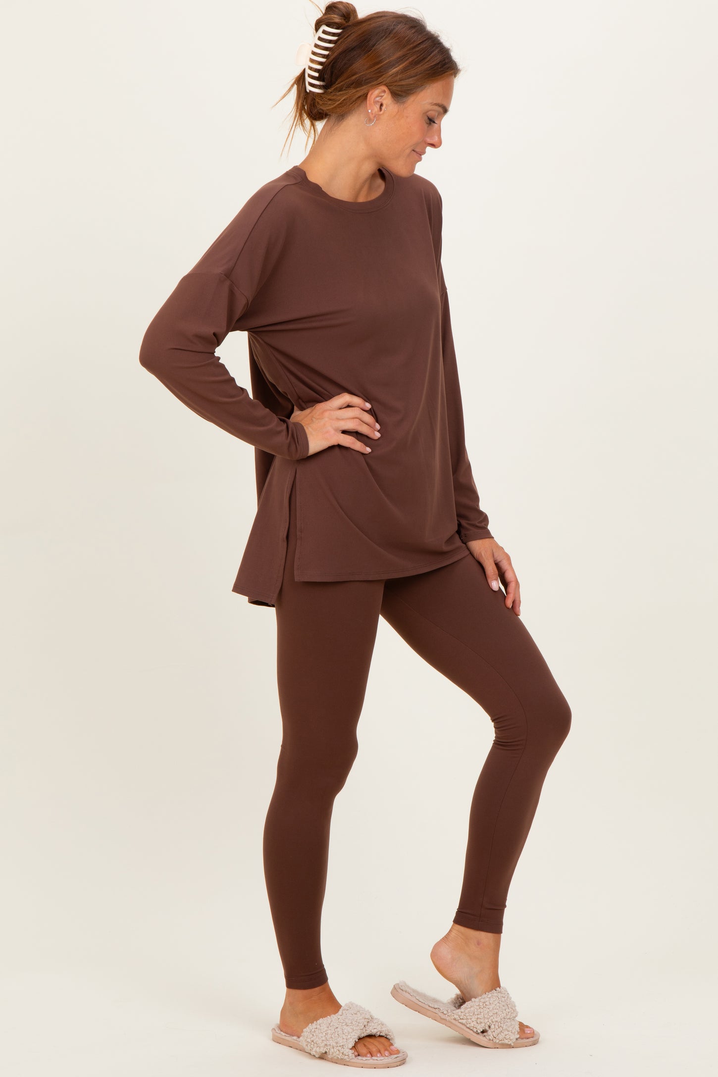 woman wearing a brown long sleeve top and matching leggings, styled with cozy slippers, standing sideways