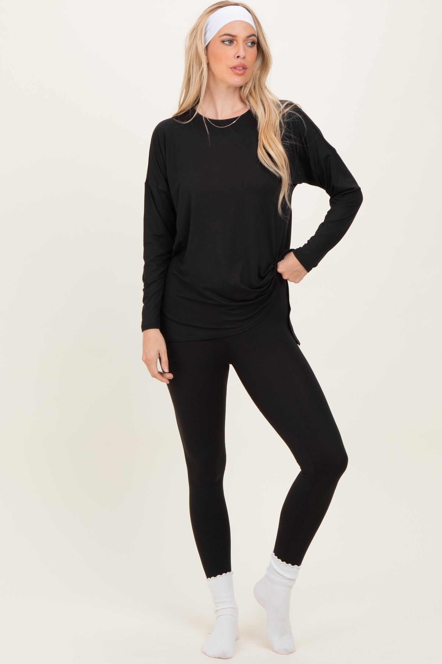 woman wearing a black long sleeve top and black leggings with a headband and white socks