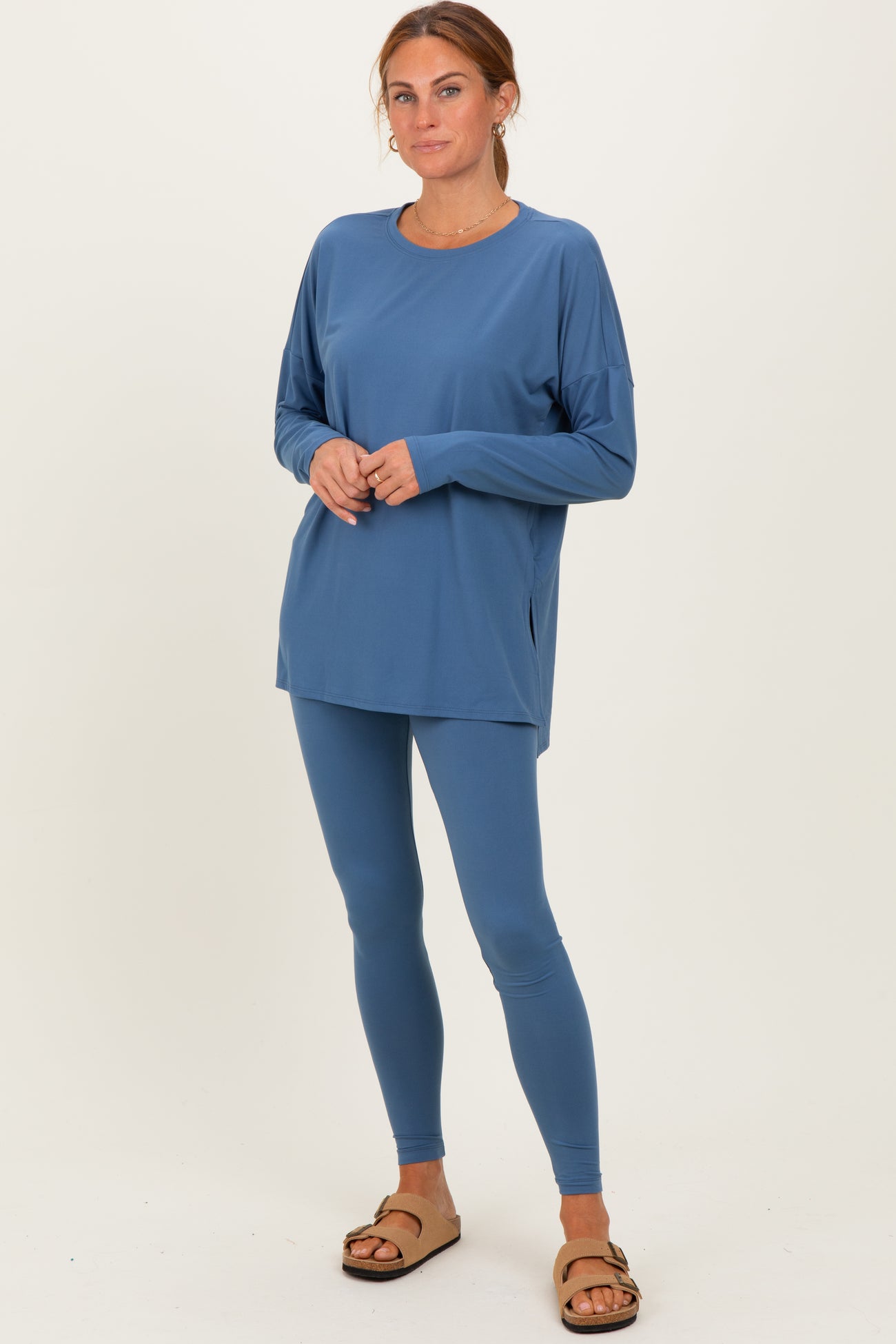 woman wearing a relaxed fit blue long sleeve top and matching leggings with brown slide sandals