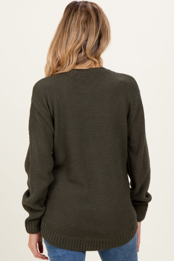 woman wearing a dark green maternity sweater with a textured pattern, showing the back view
