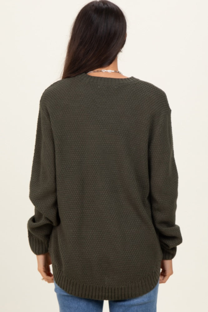 woman wearing an oversized olive green textured sweater with long sleeves and a relaxed fit