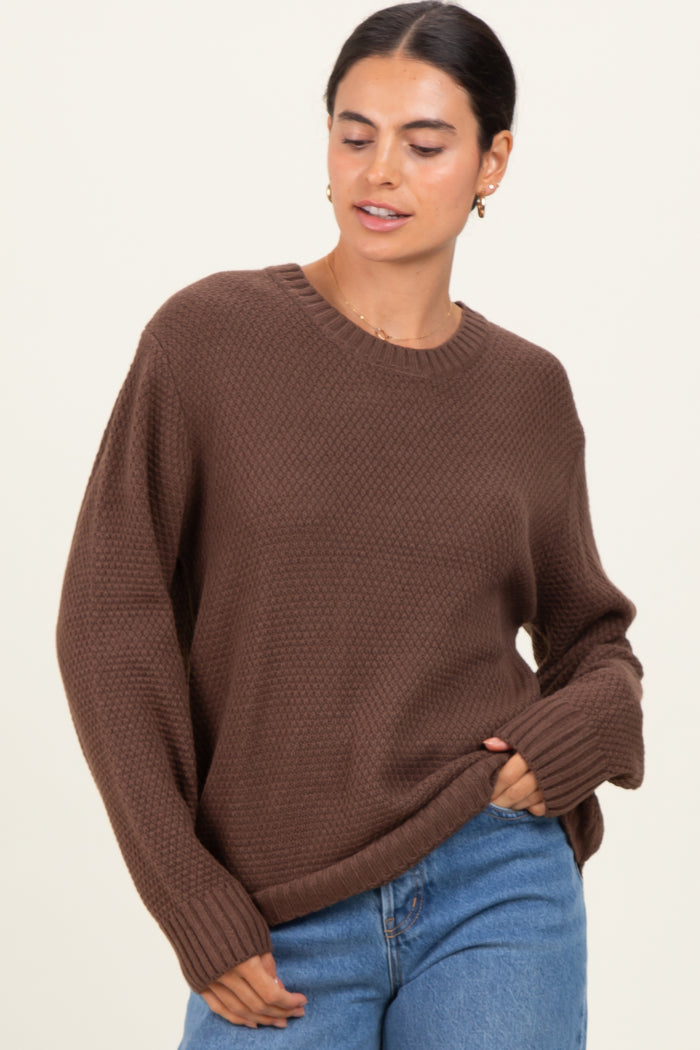 woman wearing a brown textured knit sweater and light blue jeans