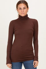 woman wearing a fitted brown long sleeve turtleneck top with a sleek design and soft fabric