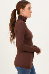woman wearing a brown long sleeve turtleneck top and blue jeans, styled in a side profile view