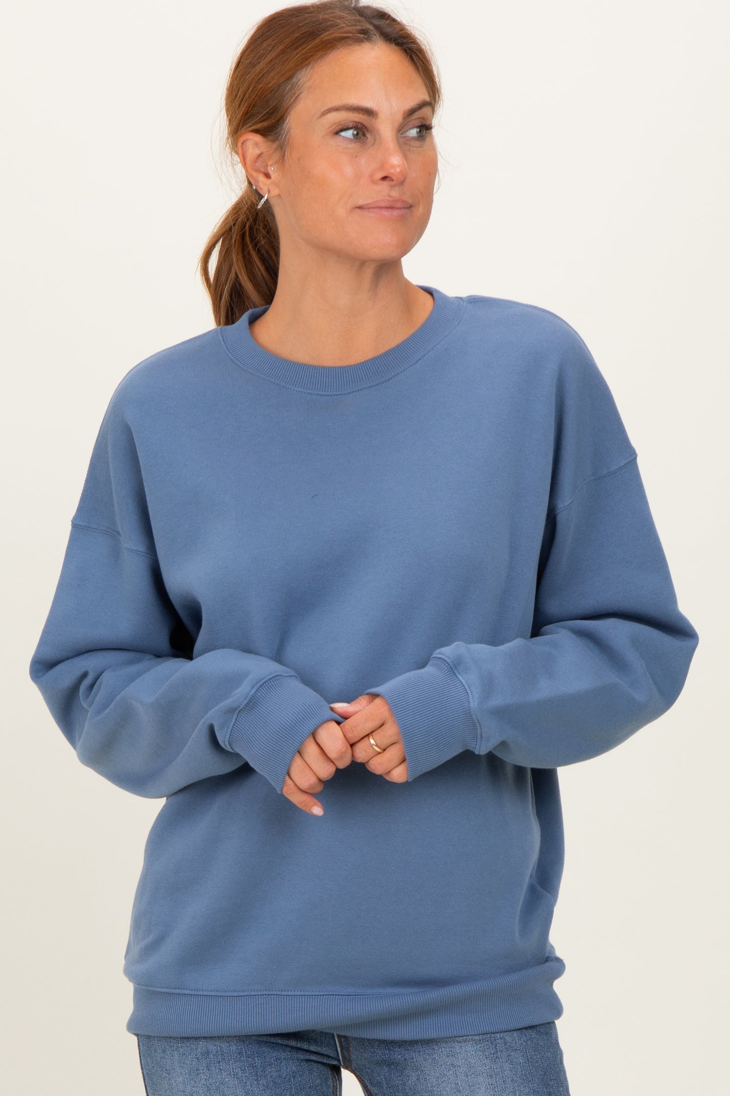 woman wearing a blue crewneck sweatshirt with dropped shoulders and long sleeves, styled with casual jeans
