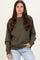 woman wearing an olive green oversized sweatshirt with a round neckline and relaxed fit, paired with light blue jeans