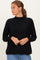 woman wearing a black long sleeve turtleneck sweater with a relaxed fit and side slits, styled with light blue jeans