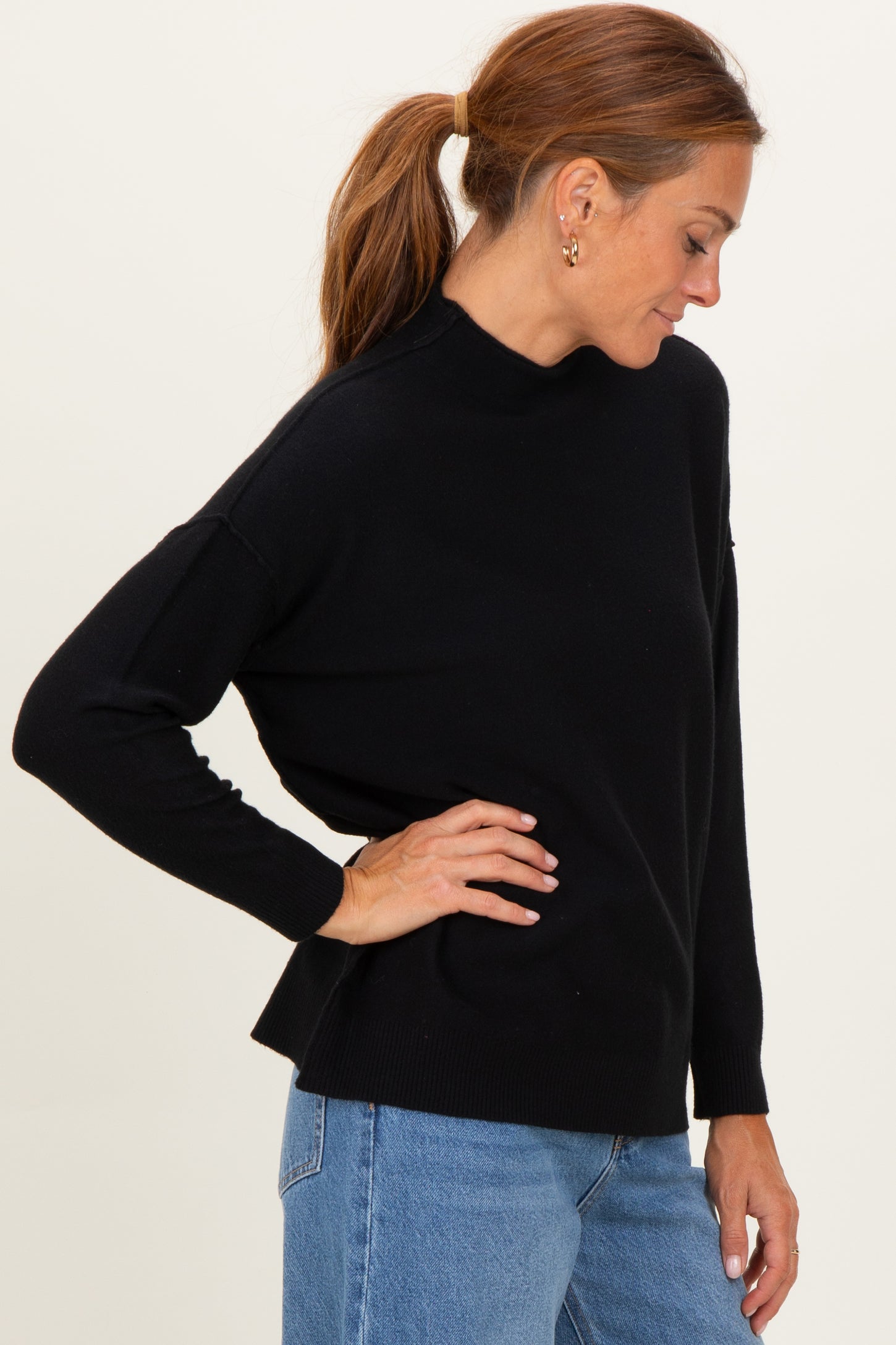 woman wearing a black long sleeve mock neck sweater paired with light blue jeans