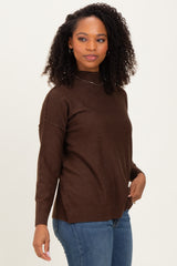woman wearing a brown turtleneck sweater with relaxed fit and long sleeves paired with blue jeans