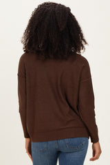 woman wearing a brown oversized sweater with long sleeves and back view, paired with blue jeans