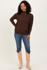 woman wearing a brown knit sweater with a relaxed fit and blue skinny jeans, paired with tall beige boots