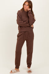 woman wearing a brown matching sweatshirt and jogger set with a relaxed fit and elastic waistband, styled with cozy slippers